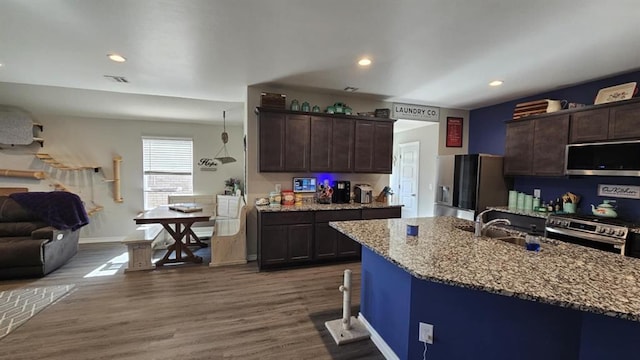 11704 SW 40th St, Mustang, OK 73064 - kitchen featuring appliances with stainless steel finishes, dark brown cabinetry, light stone counters, open floor plan, and recessed lighting