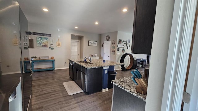 11704 SW 40th St, Mustang, OK 73064 - kitchen featuring dark wood-style floors, a center island with sink, recessed lighting, dark cabinetry, and light stone counters