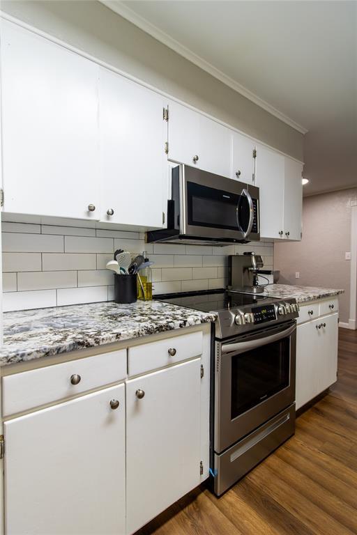 1712 N Pennsylvania Ave, Shawnee, OK 74804 - kitchen featuring appliances with stainless steel finishes, crown molding, dark wood-style flooring, white cabinetry, and backsplash