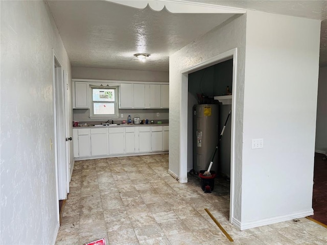104 S Ross St, Walters, OK 73572 - kitchen featuring electric water heater, white cabinetry, a textured ceiling, and light floors