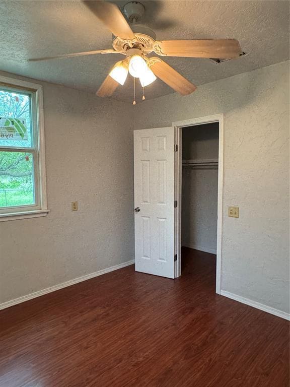 104 S Ross St, Walters, OK 73572 - unfurnished bedroom featuring wood finished floors, a textured wall, a textured ceiling, a walk in closet, and a closet