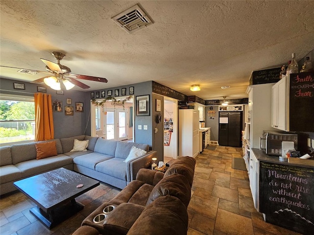 3205 NW 62nd St, Oklahoma City, OK 73112 - living room with a ceiling fan, healthy amount of natural light, stone tile flooring, and a textured ceiling