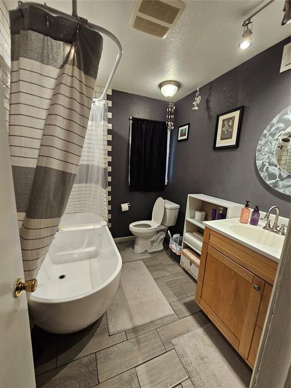 3205 NW 62nd St, Oklahoma City, OK 73112 - bathroom with vanity, a textured ceiling, a textured wall, and curtained shower