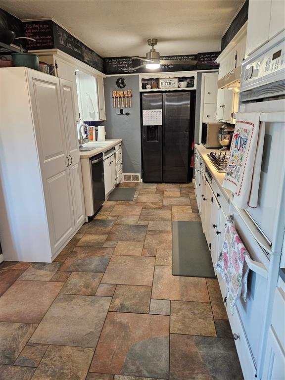 3205 NW 62nd St, Oklahoma City, OK 73112 - kitchen featuring stainless steel appliances, white cabinets, light countertops, stone finish flooring, and a ceiling fan
