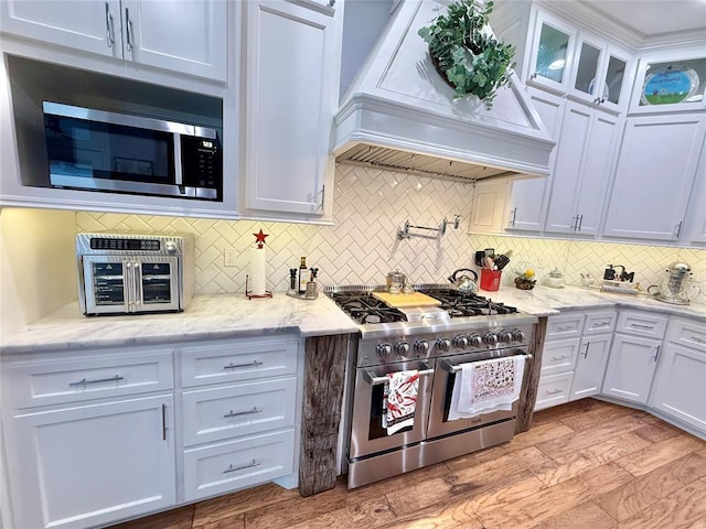 1118 Fernwood Dr, Midwest City, OK 73130 - kitchen featuring appliances with stainless steel finishes, custom exhaust hood, backsplash, and white cabinets