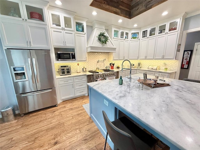 1118 Fernwood Dr, Midwest City, OK 73130 - kitchen with stainless steel appliances, premium range hood, light wood finished floors, white cabinetry, and light stone counters