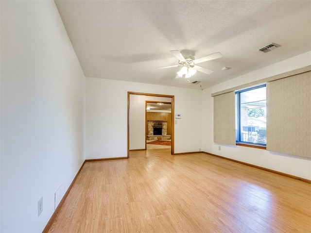 7600 NW 27th St, Bethany, OK 73008 - unfurnished room featuring light wood finished floors, a ceiling fan, a fireplace, and a textured ceiling