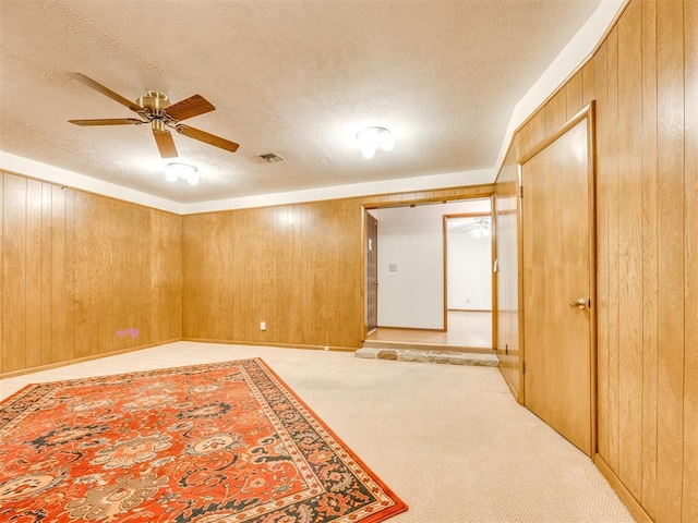 7600 NW 27th St, Bethany, OK 73008 - unfurnished room featuring wood walls, light colored carpet, a textured ceiling, and ceiling fan