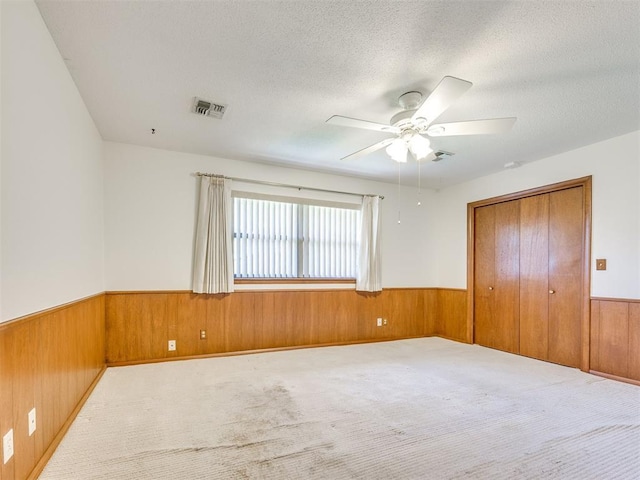 7600 NW 27th St, Bethany, OK 73008 - unfurnished bedroom with wooden walls, a wainscoted wall, a textured ceiling, carpet flooring, and a closet