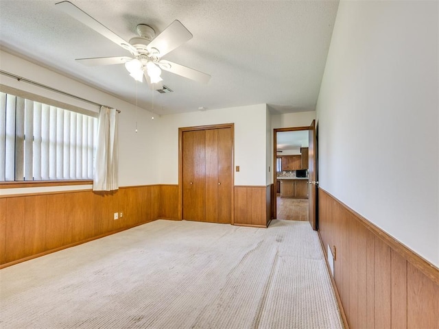 7600 NW 27th St, Bethany, OK 73008 - unfurnished bedroom featuring wood walls, a wainscoted wall, light carpet, a closet, and a textured ceiling