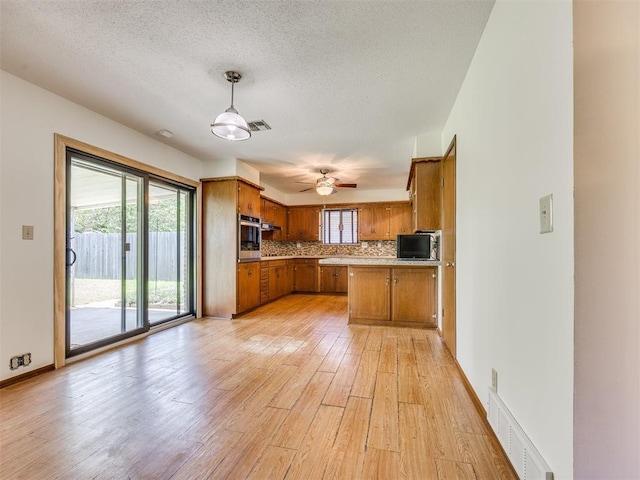 7600 NW 27th St, Bethany, OK 73008 - kitchen featuring brown cabinets, oven, light wood-type flooring, tasteful backsplash, and light countertops