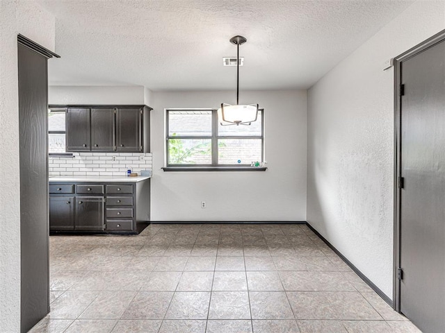 535 N Patchin Ave, Shawnee, OK 74801 - kitchen with a textured ceiling, light countertops, decorative backsplash, hanging light fixtures, and a textured wall