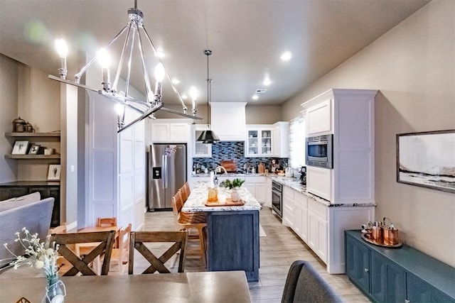 2713 Falling Leaves Dr, Weatherford, OK 73096 - kitchen with stainless steel appliances, white cabinetry, a kitchen island, light wood-style flooring, and recessed lighting