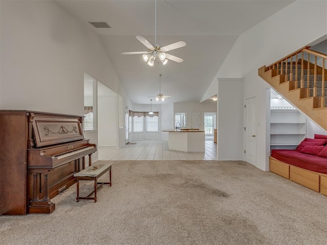 4919 E Lone Chimney Rd, Glencoe, OK 74032 - living area featuring light carpet, a ceiling fan, stairs, light tile patterned flooring, and high vaulted ceiling