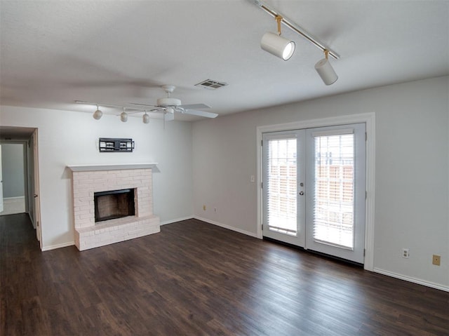 3003 River Oaks Dr Unit 119, Norman, OK 73072 - unfurnished living room featuring rail lighting, a ceiling fan, french doors, dark wood-style flooring, and a brick fireplace