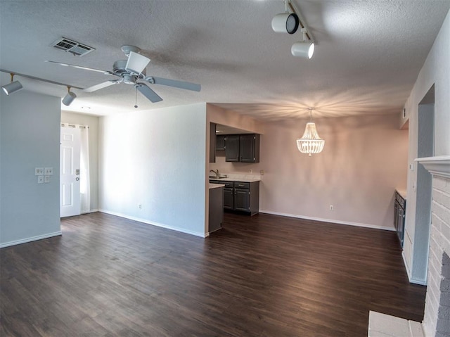 3003 River Oaks Dr Unit 119, Norman, OK 73072 - unfurnished living room with track lighting, a fireplace, a textured ceiling, and dark wood finished floors