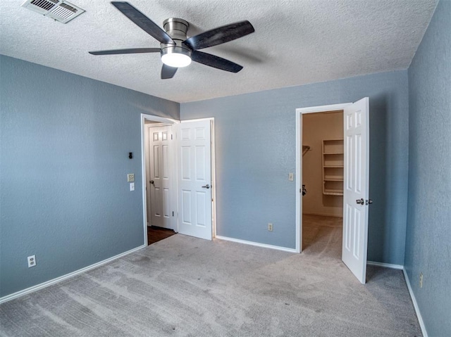 3003 River Oaks Dr Unit 119, Norman, OK 73072 - unfurnished bedroom with a textured ceiling, carpet, a spacious closet, a closet, and a textured wall