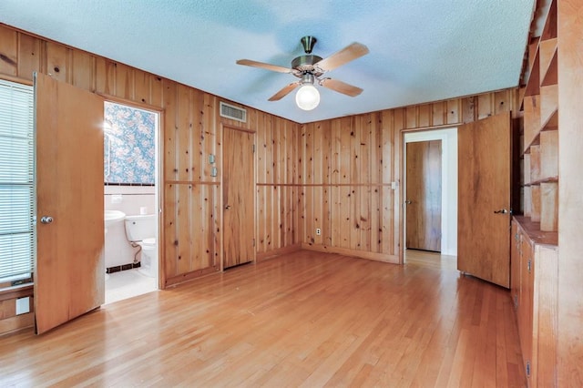 5932 N Grove Ave, Oklahoma City, OK 73122 - spare room featuring light wood-style floors, a ceiling fan, wooden walls, and a textured ceiling