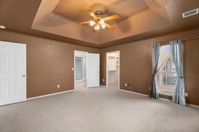 813 N Council Rd Unit S, Newcastle, OK 73065 - unfurnished bedroom with a raised ceiling, carpet flooring, a walk in closet, a textured wall, and a ceiling fan