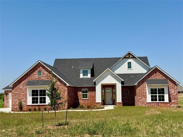 4163 Hawthorne St, Piedmont, OK 73078 - view of front of property featuring brick siding, a front lawn, board and batten siding, and a shingled roof