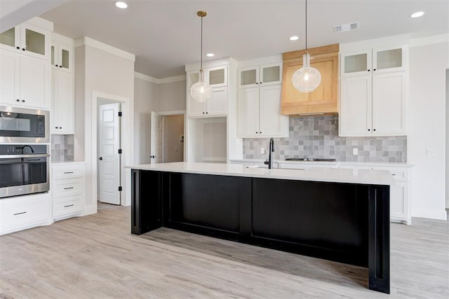 4163 Hawthorne St, Piedmont, OK 73078 - kitchen with stainless steel appliances, a kitchen island with sink, tasteful backsplash, light countertops, and light wood finished floors