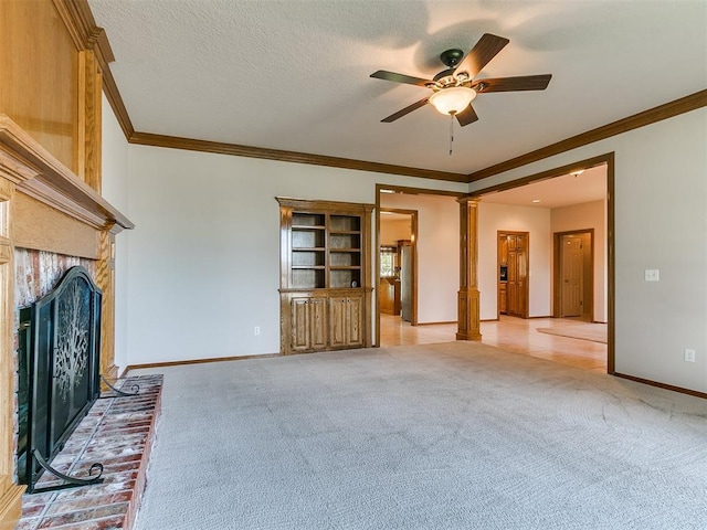 1204 Scrambler Ln, Edmond, OK 73025 - unfurnished living room featuring light carpet, ornamental molding, ceiling fan, a fireplace, and ornate columns