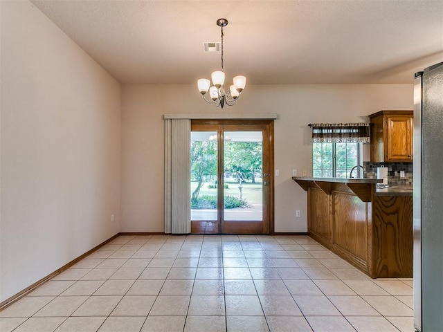 1204 Scrambler Ln, Edmond, OK 73025 - unfurnished dining area with a chandelier and light tile patterned flooring