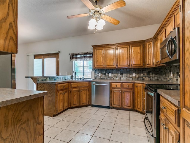 1204 Scrambler Ln, Edmond, OK 73025 - kitchen with stainless steel appliances, brown cabinets, decorative backsplash, and a peninsula