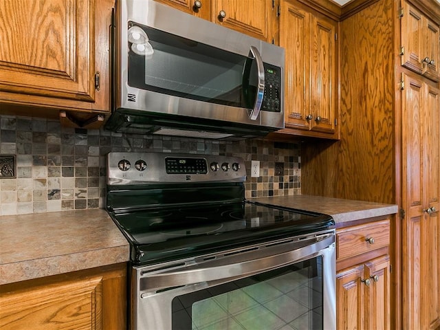 1204 Scrambler Ln, Edmond, OK 73025 - kitchen featuring stainless steel appliances, brown cabinetry, tasteful backsplash, and light countertops