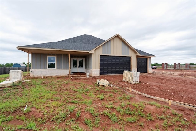 41364 Hazel Dell Rd, Shawnee, OK 74804 - view of front of house with board and batten siding, an attached garage, french doors, a shingled roof, and brick siding