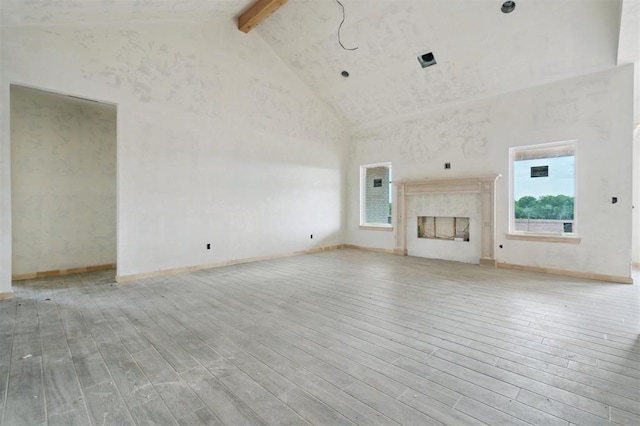 41364 Hazel Dell Rd, Shawnee, OK 74804 - unfurnished living room featuring beam ceiling, high vaulted ceiling, wood finished floors, and a premium fireplace