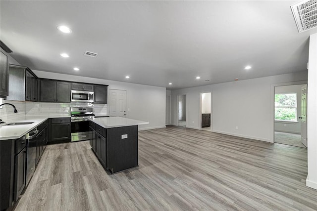 1417 Mallard Dr, Del City, OK 73115 - kitchen with appliances with stainless steel finishes, a kitchen island, light wood-style floors, light countertops, and recessed lighting
