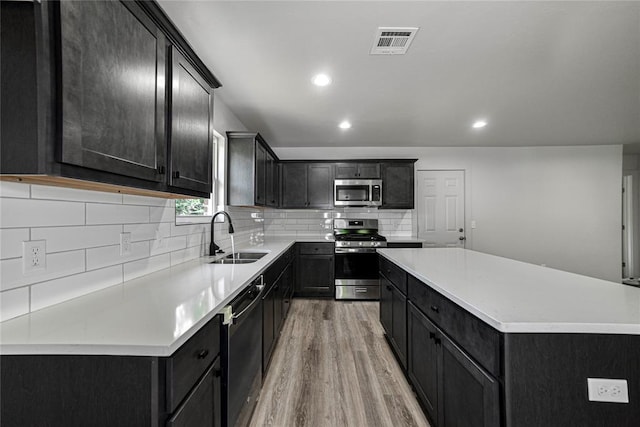 1417 Mallard Dr, Del City, OK 73115 - kitchen featuring appliances with stainless steel finishes, light wood-type flooring, tasteful backsplash, a kitchen island, and recessed lighting