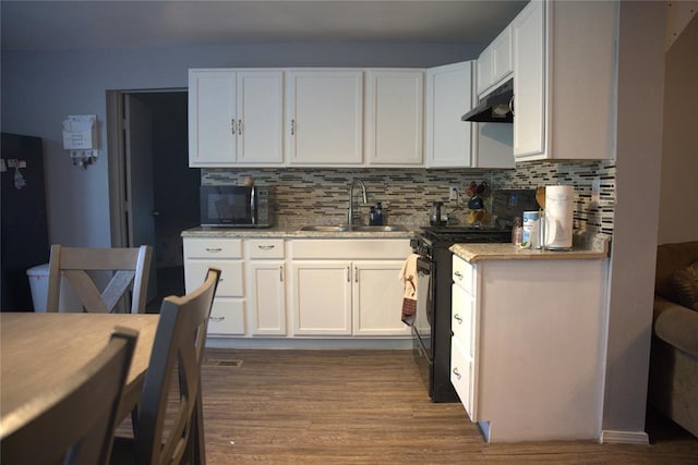9008 N Walker Ave, Oklahoma City, OK 73103 - kitchen featuring black appliances, under cabinet range hood, wood finished floors, and backsplash