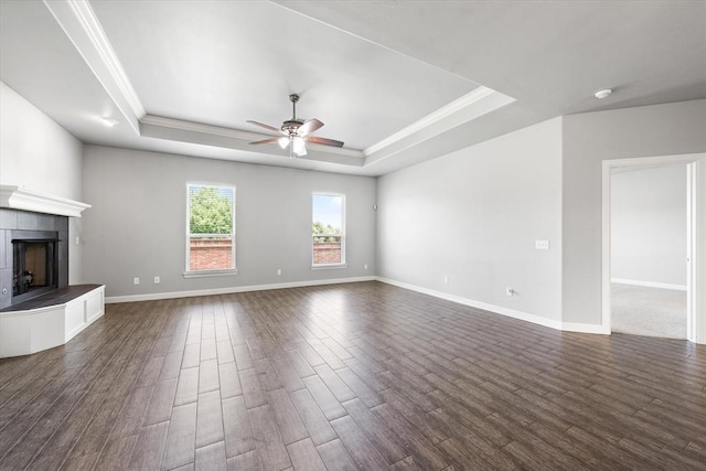 641 Geneva Dr, Edmond, OK 73025 - unfurnished living room featuring a raised ceiling, ceiling fan, crown molding, a fireplace, and dark wood-style flooring