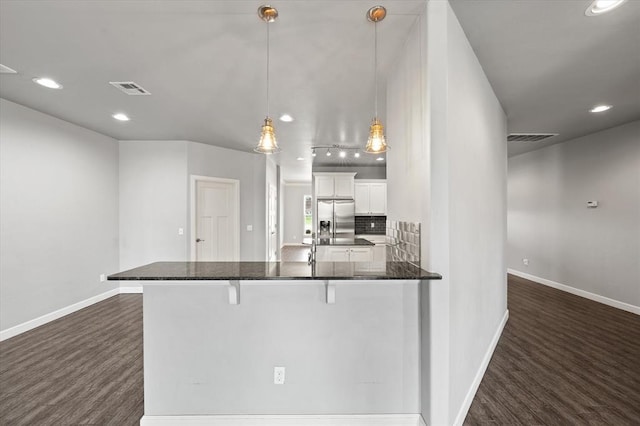 641 Geneva Dr, Edmond, OK 73025 - kitchen with stainless steel fridge, dark wood-style floors, recessed lighting, white cabinetry, and a kitchen breakfast bar