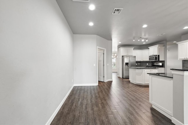 641 Geneva Dr, Edmond, OK 73025 - kitchen with stainless steel appliances, dark countertops, a center island, backsplash, and dark wood finished floors