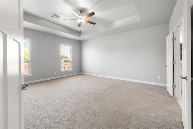 641 Geneva Dr, Edmond, OK 73025 - spare room with a tray ceiling, ceiling fan, and carpet