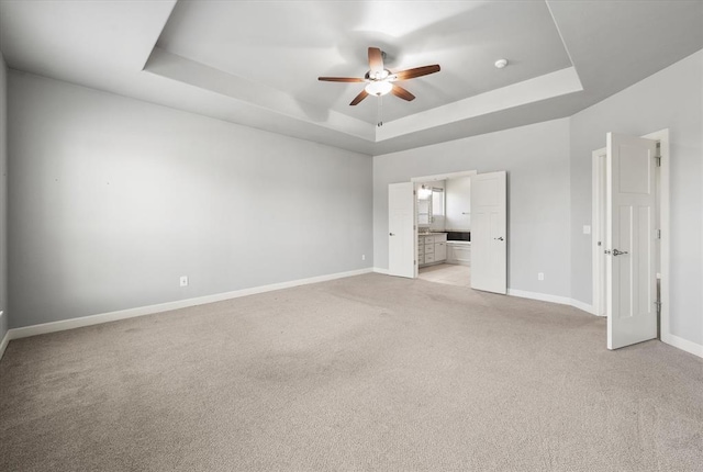 641 Geneva Dr, Edmond, OK 73025 - unfurnished bedroom featuring a raised ceiling, light colored carpet, connected bathroom, and a ceiling fan
