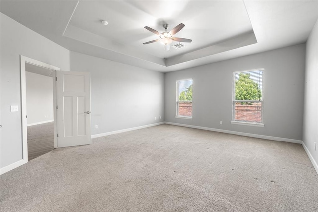 641 Geneva Dr, Edmond, OK 73025 - spare room featuring a raised ceiling, ceiling fan, carpet floors, and a smoke detector