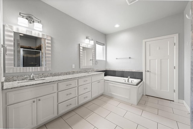 641 Geneva Dr, Edmond, OK 73025 - full bathroom featuring double vanity, a garden tub, tile patterned floors, and a stall shower