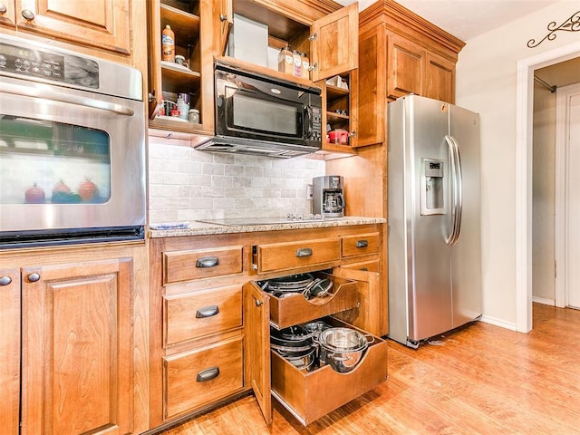 2349 Fox Ln, Blanchard, OK 73010 - kitchen with appliances with stainless steel finishes, light wood finished floors, brown cabinets, decorative backsplash, and light stone countertops