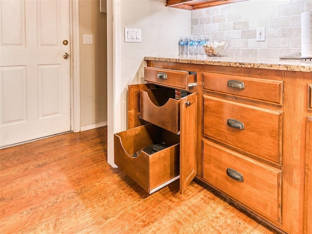2349 Fox Ln, Blanchard, OK 73010 - detailed view of brown cabinets, tasteful backsplash, light wood-style floors, and light stone counters