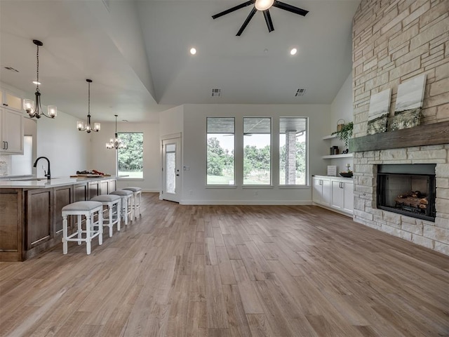 7625 Leoma Ln, Oklahoma City, OK 73150 - living room featuring a chandelier, high vaulted ceiling, a fireplace, light wood-style floors, and ceiling fan