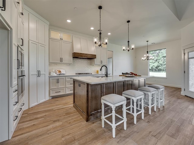 7625 Leoma Ln, Oklahoma City, OK 73150 - kitchen with a chandelier, light wood finished floors, a breakfast bar, stainless steel oven, and recessed lighting