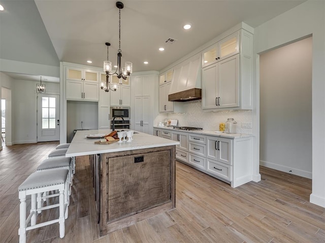 7625 Leoma Ln, Oklahoma City, OK 73150 - kitchen featuring a chandelier, custom exhaust hood, appliances with stainless steel finishes, white cabinets, and glass insert cabinets