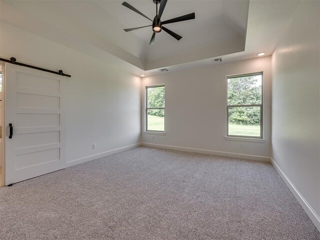 7625 Leoma Ln, Oklahoma City, OK 73150 - carpeted spare room with a barn door, ceiling fan, and a tray ceiling