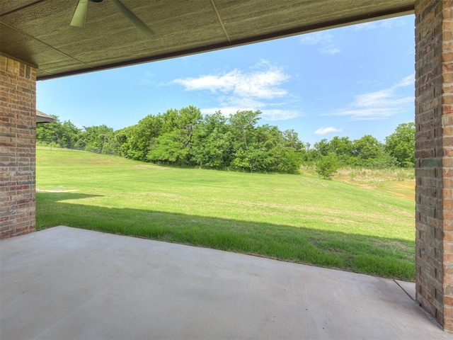7625 Leoma Ln, Oklahoma City, OK 73150 - view of grassy yard with ceiling fan, a patio area, and view of wooded area
