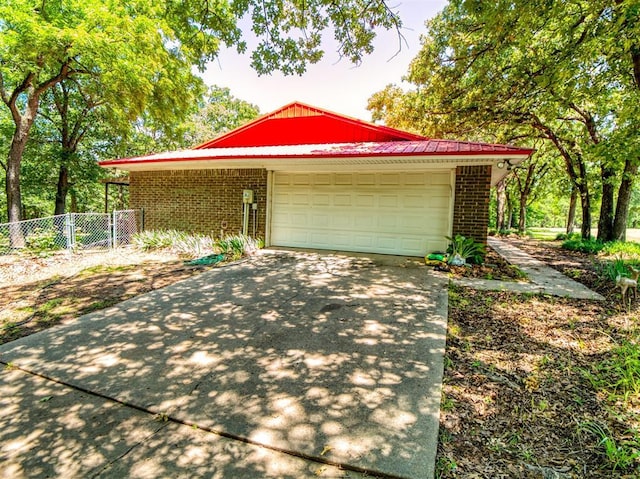114 Timber Ln, Mcloud, OK 74851 - view of front of home featuring brick siding, concrete driveway, an attached garage, and a metal roof