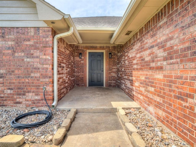 3922 Deer Xing, Edmond, OK 73025 - view of exterior entry featuring brick siding and a shingled roof